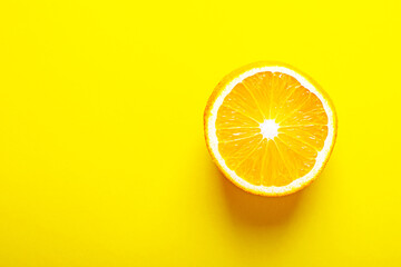 Half an orange close-up on illuminating yellow background.