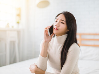 unhappy young woman talking on mobile phone at home