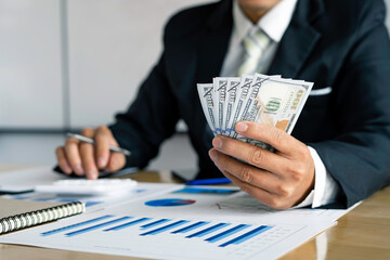 Businessman accountant counting money and making notes at report doing finances and calculate the...
