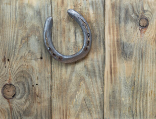 An old horseshoe taken from a horse and nailed to old planks with hammering nails.