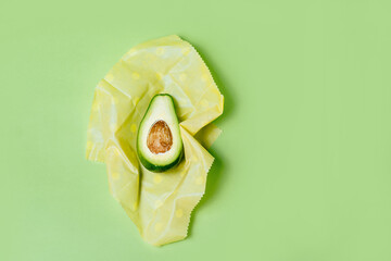 Organic fabric covers for food storage. Reusable Beeswax Food Wraps with half of avocado on green...