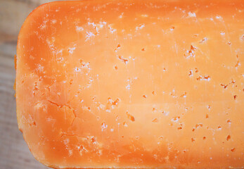 Farmer's cheddar cheese with grains inside. texture as hand-made cheeses ripen. orange white solid aged cheese background