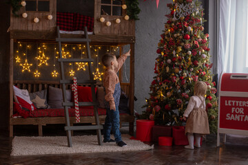 brother shows little sister toys on the Christmas tree
