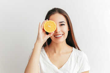 Beautiful Asian smiling brunette girl with an fruit orange in her hands on a white background