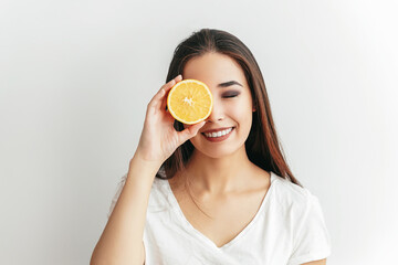 Beautiful Asian smiling brunette girl with an fruit orange in her hands on a white background