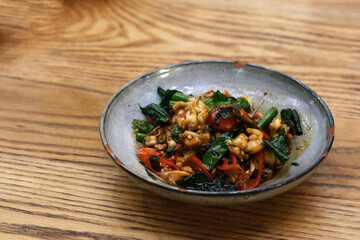 close up spicy bull frog in plate on patterned wooden table. Traditional Thai food