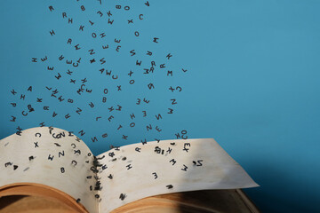 Letters of the alphabet in levitation in the air over the open book pages