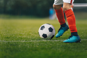 Soccer Players Legs. Footballer Kicking Ball on Natural Grass Field. Closeup Image of Soccer Boy in...