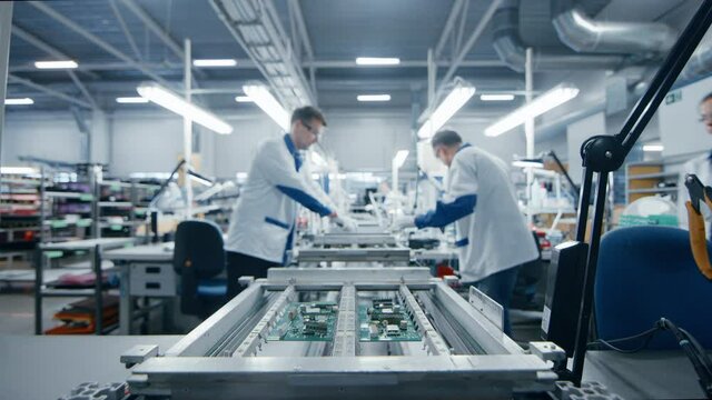 Modern High-Tech Electronics Factory Moving Manufacturing Conveyor: Professionals Doing Precision Work Assemble Circuit Boards, Processors, Microchips, Semiconductors