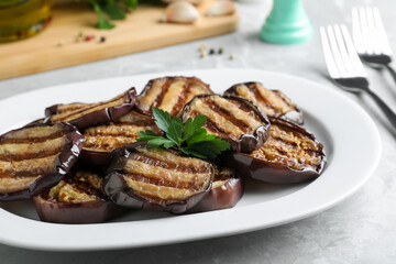 Delicious grilled eggplant slices served on grey table, closeup