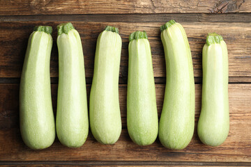 Raw green zucchinis on wooden table, flat lay