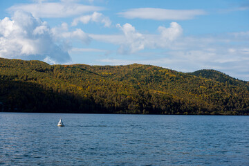 Fototapeta na wymiar Lake Baikal in autumn. Water and mountains on a sunny day. green forest and warmth