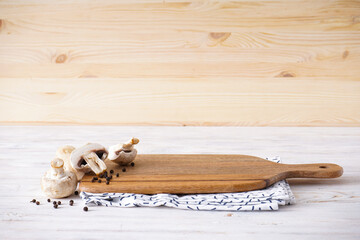Wooden cutting board and kitchen towel on a wooden background, place for text.