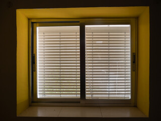 WINDOW WITH VERY OLD BLIND, LETTING LIGHT IN THROUGH THE SLITS