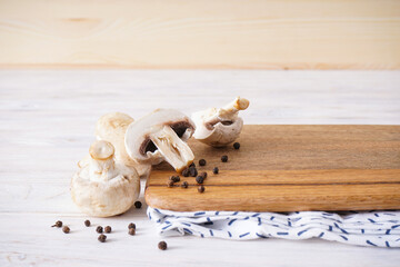 Wooden cutting board and mushrooms on a wooden background, space for text.