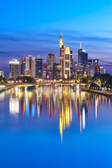 Fototapeta na wymiar Nicely illuminated skyline of Frankfurt, Germany, in the evening with reflections on the river Main