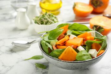 Delicious persimmon salad served on white marble table, closeup