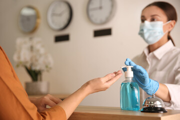 Obraz na płótnie Canvas Woman applying antiseptic gel at hotel reception, closeup