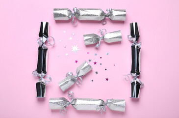 Silver Christmas crackers and shiny confetti on pink background, flat lay