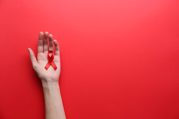 Woman holding red awareness ribbon on color background, top view with space for text. World AIDS disease day