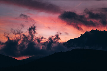 saturated orange-purple mountain landscape with clouds during twilight.