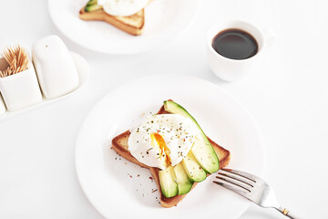 Toast with poached eggs and avocado. Healthy breakfast and food. Cozy morning. Nutrition for pregnant. Diet for women. Breakfast in hotel room or bed. Scrambled eggs sandwich.