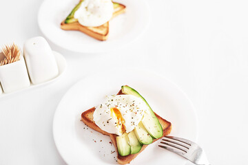 Toast with poached eggs and avocado. Healthy breakfast and food. Cozy morning. Nutrition for pregnant. Diet for women. Breakfast in hotel room or bed. Scrambled eggs sandwich.