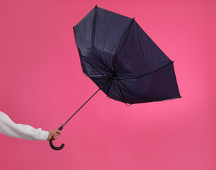 Woman with umbrella caught in gust of wind on pink background, closeup