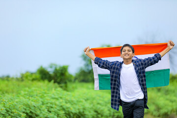 Cute little boy waving Indian National Tricolor Flag over nature background