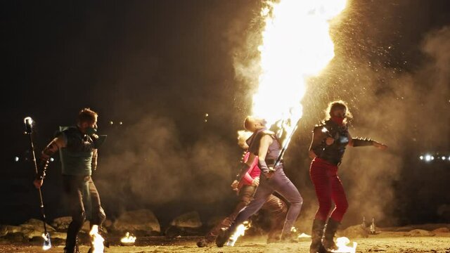Wide shot of five powerful fire artists of mixed-gender performing together.