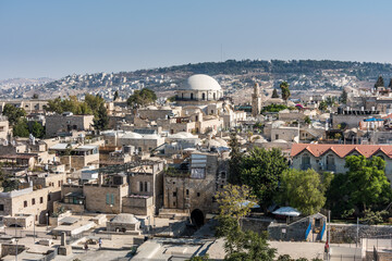 Fototapeta na wymiar Aerial view of rooftops of traditional buildings and Hurva Synagogue in the old city with blue sky of Jerusalem. View from the Lutheran Church of the Redeemer.
