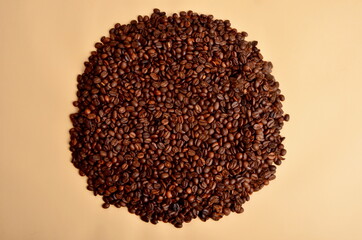 Round coffee beans stack on a beige background, copy space