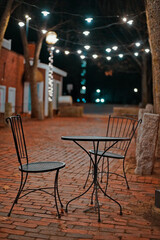Outdoor Cafe With Porch Lights Over A Chair And Table At Night On A Brick Pathway In Dover NH (New Hampshire)