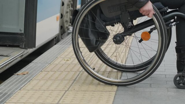 Woman in wheelchair at a bus stop goes out from bus / close up