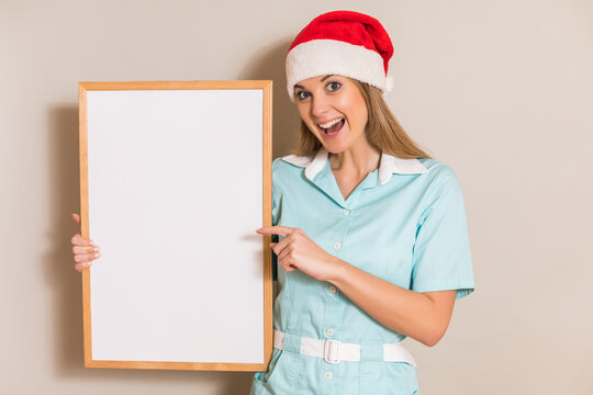 Portrait Of Nurse With Santa Hat Pointing At White Board.