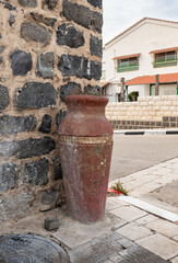 Fototapeta na wymiar The large jug with plants stands on the street corner in the Muslim Circassian - Adyghe village Kfar Kama, located near the Nazareth in the Galilee, in northern Israel