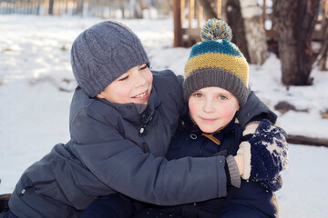 Fototapeta na wymiar The boy laughs and hugs his brother on the street in winter.