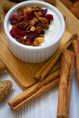 Homemade granola with cinnamon, nuts and cranberries on a white table