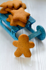 Gingerbread cookie in the form of a man, trees and stars on a blue sled, background with a copy space