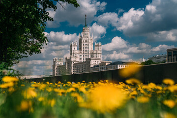 High-rise building on Kotelnicheskaya Embankment summer view with flowers, people riding bicycles, blue sky . Moscow, Russia. 