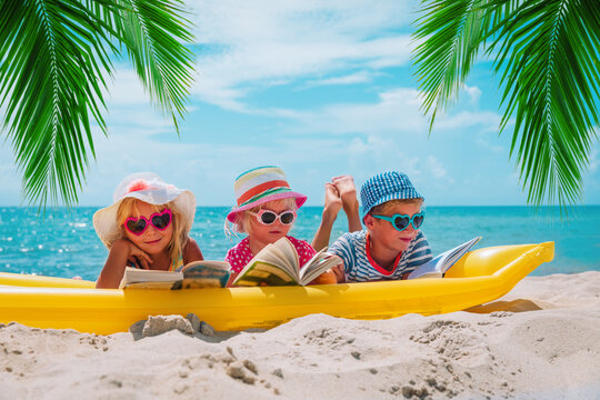 happy kids- boy and girls read books on beach, family vacation