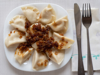 Ruthenian dumplings - a type of dumplings popular in Poland and Ukraine, otherwise known as Galician dumplings with fried onion, arranged on a white plate