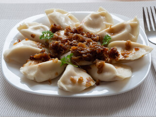 Ruthenian dumplings - a type of dumplings popular in Poland and Ukraine, otherwise known as Galician dumplings with fried onion, arranged on a white plate