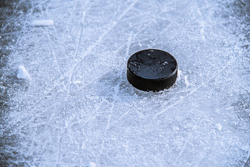 black hockey puck lies on ice at stadium