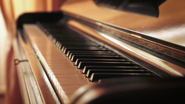 Detail of keys of an old Blüthner grand piano by large window with curtains, tripod rack focus.