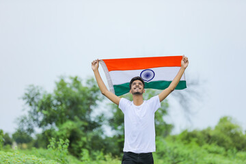 Young indian man waving indian national flag over nature background