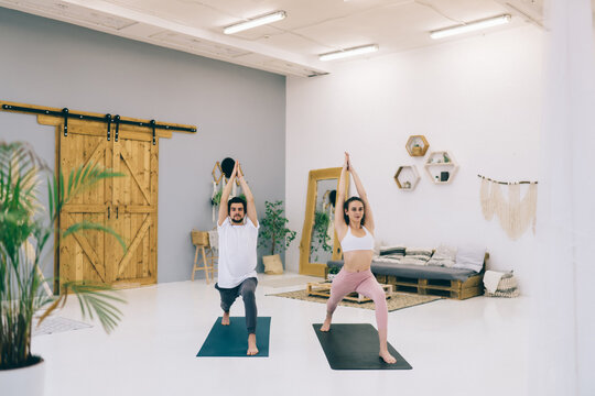 Young couple practicing yoga in modern studio