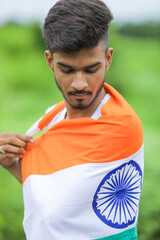 Young indian man waving indian national flag over nature background