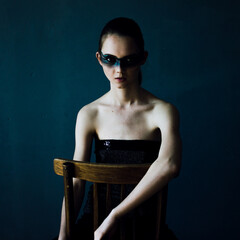 Young woman with makeup and a fashionable hairstyle poses in studio on black background