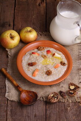Oatmeal with milk, nuts and apples on a wooden table